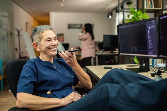 Smiling woman using voice command at desk in modern office