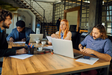 Fototapeta premium Coworkers collaborating with laptops in modern office