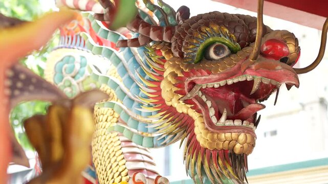 Detailed Chinese dragon sculpture decorated on a temple pillar in daylight.