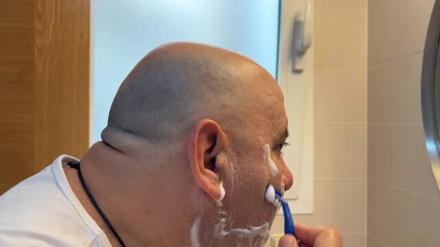 Detalle de hombre afeit&aacute;ndose en el ba&ntilde;o