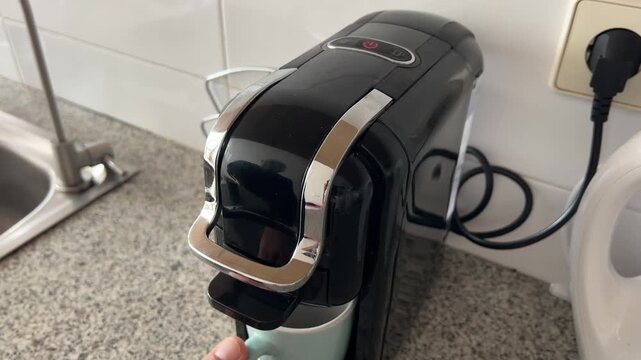 Dedo encendiendo cafetera y revelando la taza de caf&eacute;