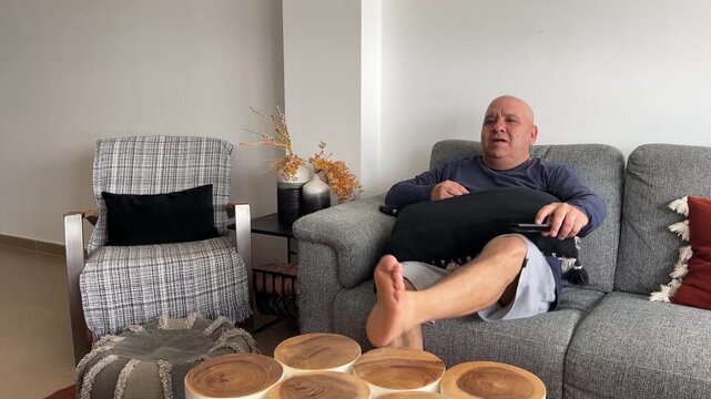 Hombre sent&aacute;ndose en el sof&aacute; para ver la tele y relajarse