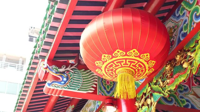 Traditional red Chinese lanterns hanging in a row at a shrine entrance.