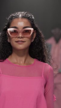 Stage, runway model and woman on walk, performance or showcase of clothes, confident and sunglasses. Advertising, outfit and person with stylish dress, bold and colorful with eyewear on fashion show