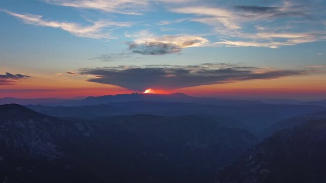 Sun setting over mountain with dramatic clouds. Beautiful evening sky at sunset. Durmitor park in Montenegro, aerial view 4k