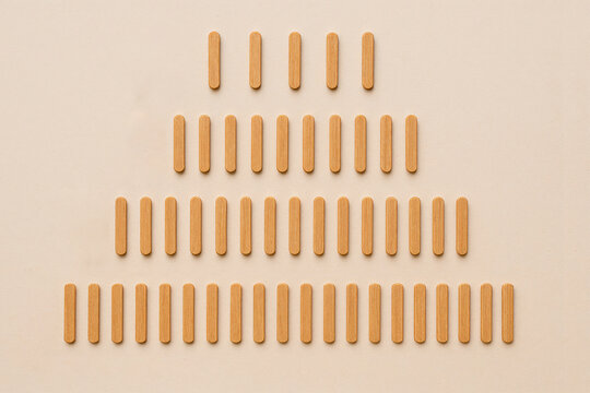 Wooden counting sticks neatly arranged in structured rows on neutral background. Minimalist math learning concept, early education, numeracy skills and organization system.