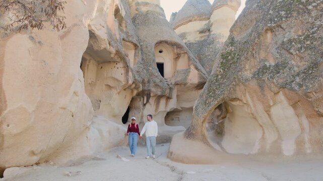Wander through the stunning rock formations and ancient cave homes in Cappadocia, Turkey. a couple of man and woman visit Pasabag Monks Valley 