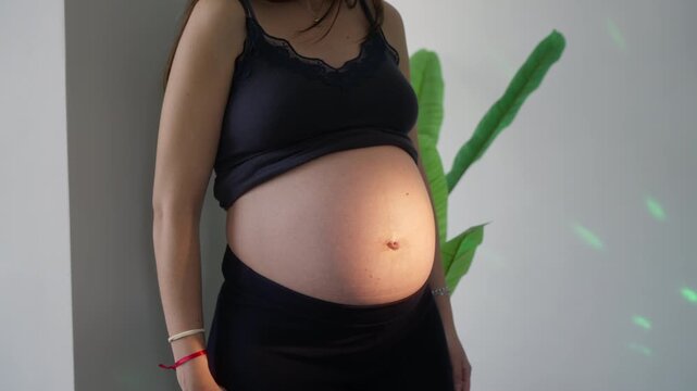 Pregnant woman bare belly in black lace top, cinematic slider shot with warm light, slow and smooth camera movement