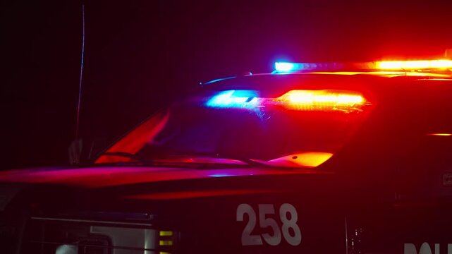 Police vehicle with activated red and blue emergency lights flashing in darkness in Durango, Mexico. Unit number 258 visible on door with light bar illuminating the night scene.