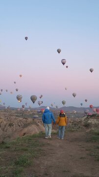 Hand in hand, a couple strolls through the stunning hills of Cappadocia.