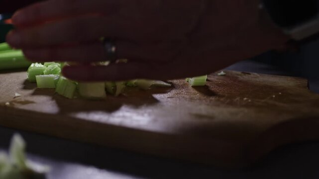 Detail of woman hand cutting celery stalks on cutting board. Home preparing food for cooking, lifestyle