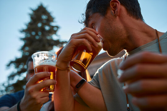 People holding beer cups and enjoying summertime outdoors.