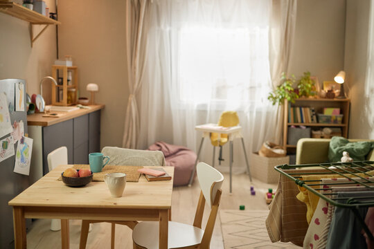 Wide shot of modest family apartment showing dining table, drying laundry, child drawings, suggesting financial hardship and daily survival. Ideal for poverty, cost of living, social support campaigns