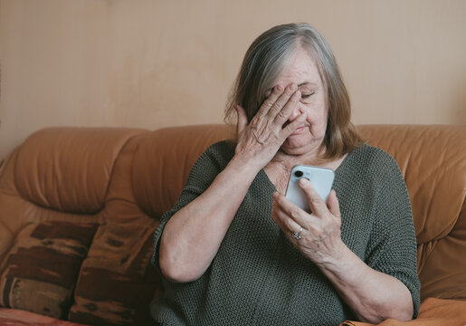 Happy elderly senior mature woman is using mobile phone or smartphone, online video call talk with waving hand, greeting her relatives and grandchildren.