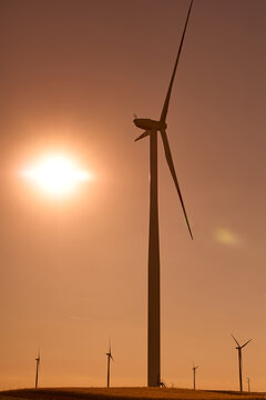 Wind turbines at sunset in green field &ndash; renewable energy, clean power, sustainable future.