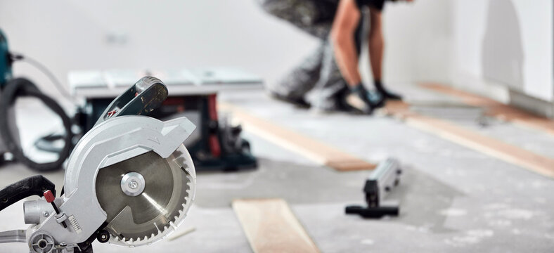 Professional handyman installing laminate flooring in a new apartment.