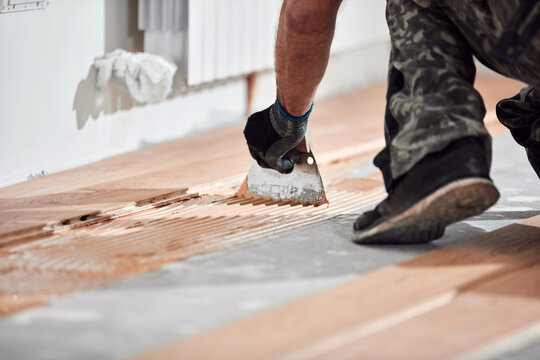 Professional handyman installing laminate flooring in a new apartment.