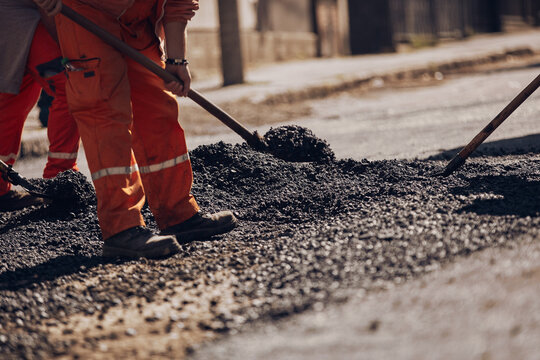 Construction worker working on a new asphalt layer on a public street.