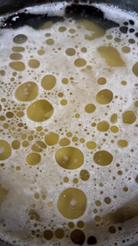 Close up of boiling pasta water with white foam and bubbles
