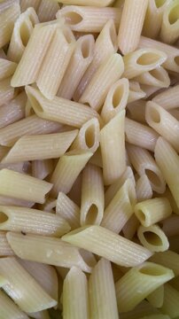 Cooked penne pasta close-up filling frame vertical format background