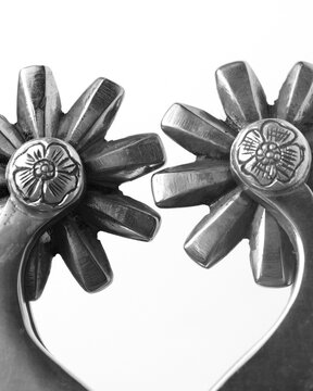Closeup detail of metal spurs showing rowels and engraving detail in black and white for western industry.