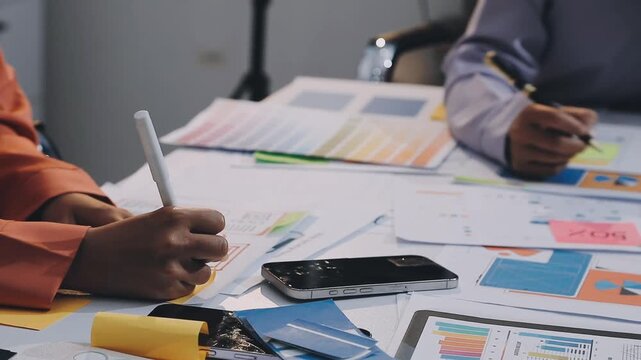Asian women working together as web designers in an office, pointing at whiteboard with uxui mobile app wireframe
