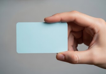 Fototapeta premium Hand holding a blank light blue business card for mockup