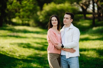 Obraz premium Couple enjoying a sunny day in a lush green park, embracing in nature