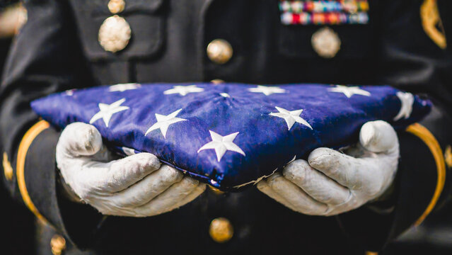 Folded flag held carefully in ceremonial military hands