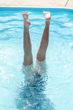 Legs doing a handstand in blue swimming pool water