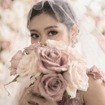 Pink rose bouquet held by an East Asian bride wearing a mesh veil looking at the camera for wedding invitations, bridal magazine covers and floral advertising