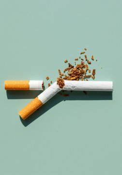 Broken cigarette with spilling tobacco on a green background for world no tobacco day, anti-smoking campaigns and health awareness blog articles with copy space