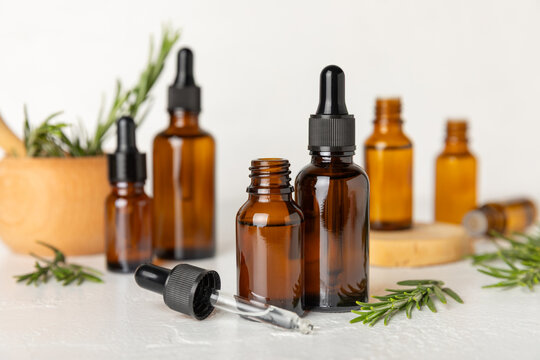 Rosemary essential oil on a textured background. Rosemary essential oil with fresh leaves nearby. Green rosemary sprig. Natural medicine, organic hair product, skin care, spa therapy. Beauty concept. 