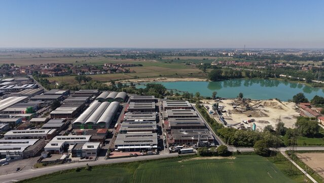 Industrial Landscape Under the Sky: A vast industrial complex sprawls across the foreground, with factories and warehouses. San Giuliano Milanese, Lombardy, Italy, 