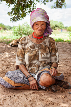 Elderly San Bushman Woman Sitting on Sand in Rural Botswana Village Africa