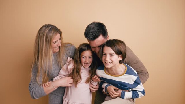 Cheerful parents with their son and daughter having fun together. Mom and dad tickling their children, creating a moment of pure joy