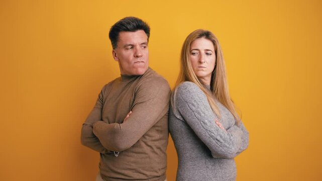 Offended middle aged man and woman standing with their arms crossed, refusing to look at each other. Couple having relationship problems