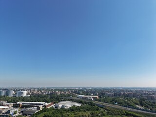 Obraz premium Urban Panorama under Clear Skies: A high-angle perspective showcases an expansive cityscape stretching towards the horizon, framed by a vast, cloudless blue sky. San Donato Milanese, Milan, Italy. 