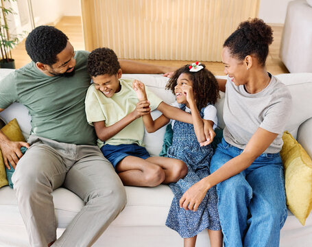 Portrait of a happy black family mother father and kids at home on couch