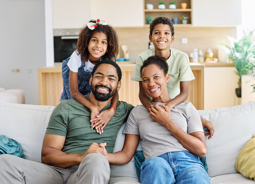 Portrait of a happy black family mother father and kids at home on couch