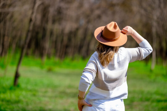 Confident woman in hat standing in forest. Nature exploration and peaceful outdoor solitude.