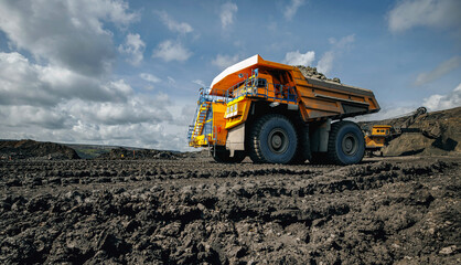 Massive dump truck at open pit coal mine under blue sky © Parilov