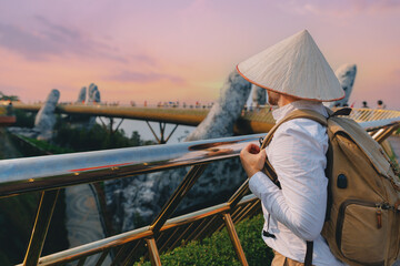 Naklejka premium Man traveler tourist at golden bridge, ba na hills, Da nang, Vietnam sunset view