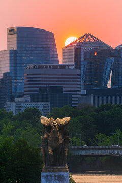 View of the Rosslyn skyline at sunset with modern skyscrapers and the Sacrifice statue in the foreground over the Potomac River in Arlington, Virginia, United States.
