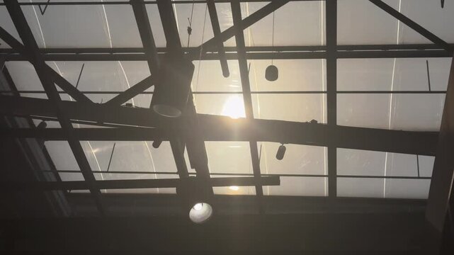Sunlight Rays Through Industrial Glass Roof in Modern Interior 4K. Cinematic sunlight rays shining through large glass roof windows in an industrial modern interior. 