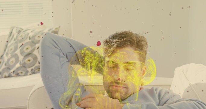 Reclining man wearing pale blue long-sleeve resting on sofa in lounge, showing yellow skull overlay