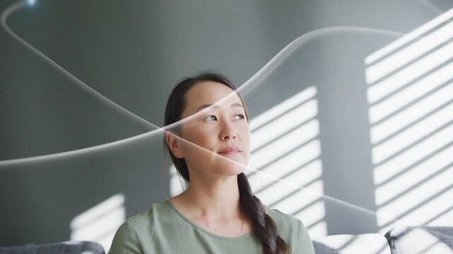 Woman sitting on sofa, eyes tracking glowing ribbons sweeping across face, serving home design mood