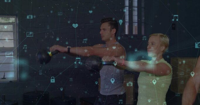 Swinging two adults in sleeveless tops performing kettlebell holds in dim gym, with digital overlay