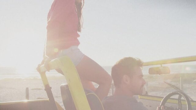 Bright sun drawing woman climbing yellow roll bar, driver steering, both seeking ocean horizon