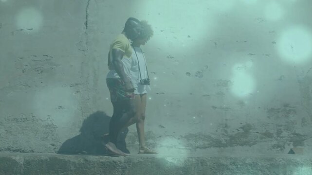 Travel photog and woman stepping on ledge, steadying for balance while teal haze drifting on wall